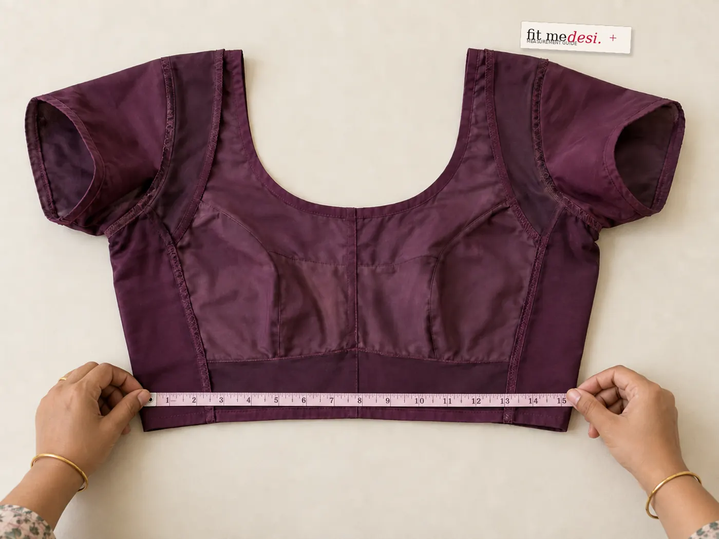 Hands measuring an inside-out blouse with a measuring tape